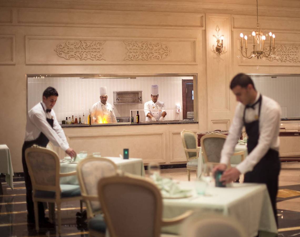 Servicepersonal im Restaurant des Sunrise Arabian Beach Resort, das Tische deckt.