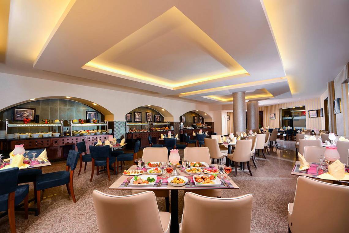 Innenbereich eines Restaurants im Pickalbatros Royal Moderna Resort mit vielen gedeckten Tischen und Stühlen.