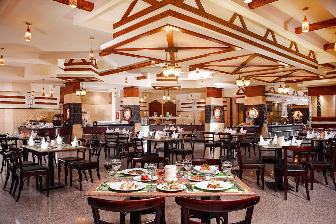Innenansicht des Restaurants im Pickalbatros Royal Moderna Resort mit gedeckten Tischen und Stühlen.