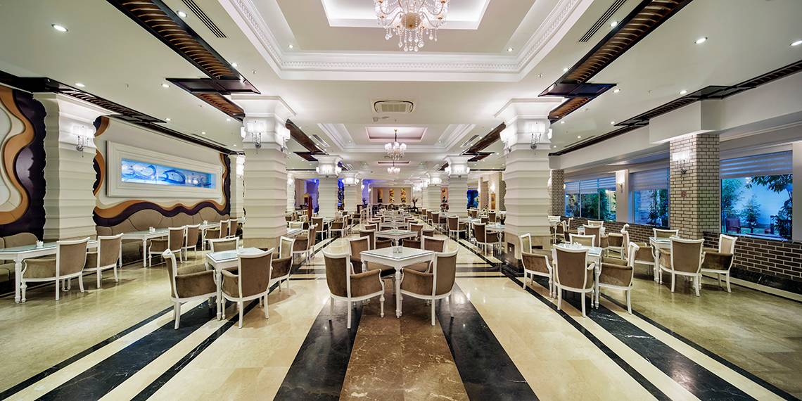 Innenbereich eines Restaurants im Crystal Waterworld Aqua Collection Hotel mit vielen Tischen und Stühlen.