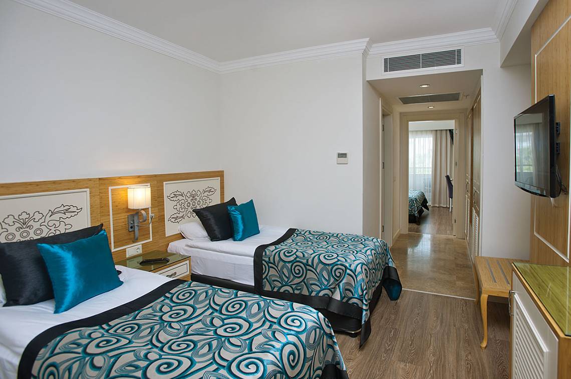 Zwei stilvolle Zimmer im Crystal Waterworld Aqua Collection Hotel mit Doppelbetten, Nachttischen und Fernsehern.
