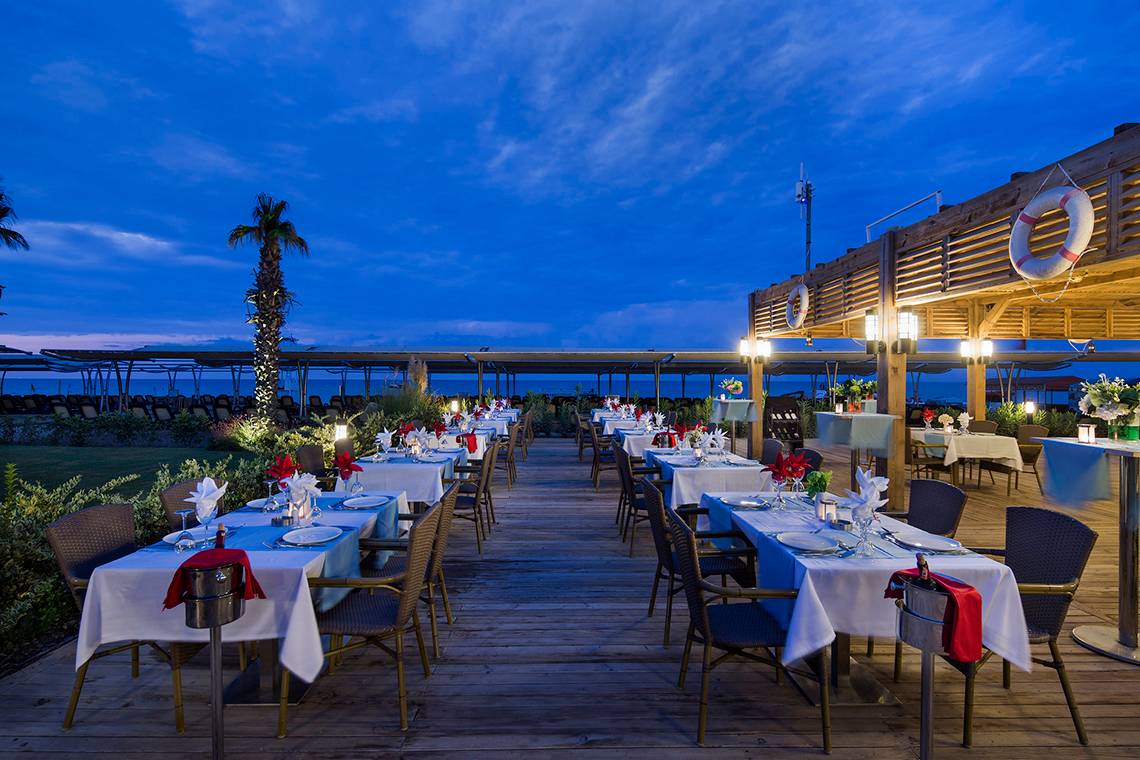 Außenbereich des Crystal Waterworld Aqua Collection Hotels mit gedeckten Tischen und Stühlen bei Nacht.