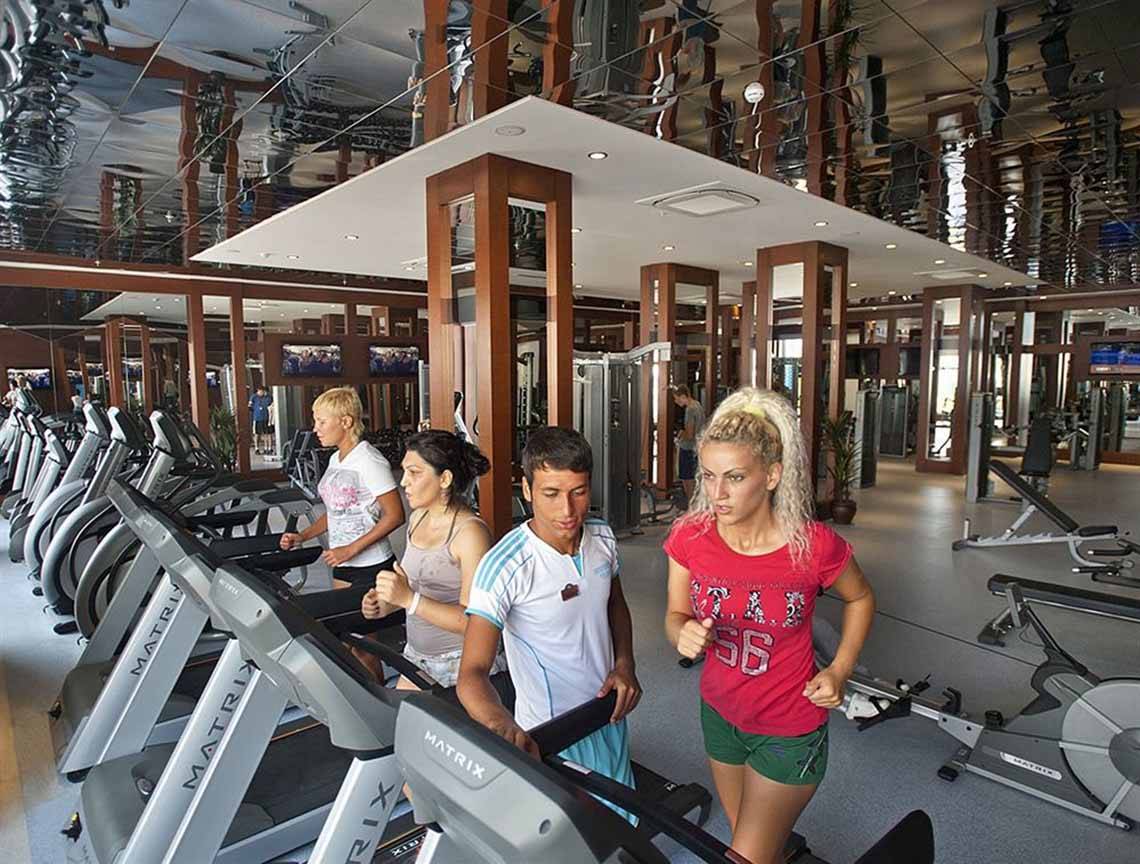 Fitness-Center im Crystal Waterworld Aqua Collection Hotel mit mehreren Personen auf Laufbändern.