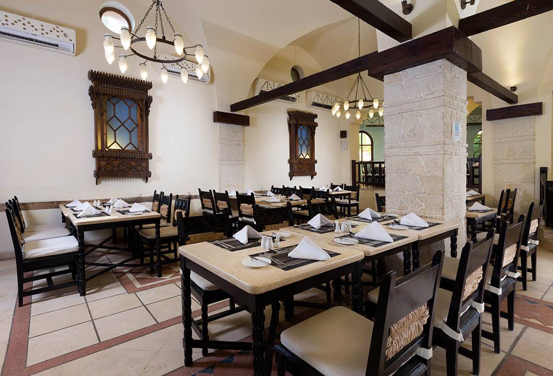 Innenansicht des Restaurants im Sultan Bey Resort mit gedeckten Tischen und dekorativen Wandelementen.