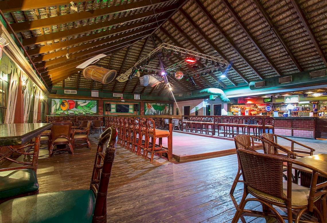 Innenansicht der Bar im Marien Puerto Plata Hotel mit Holzboden, Möbeln und einer Theke.