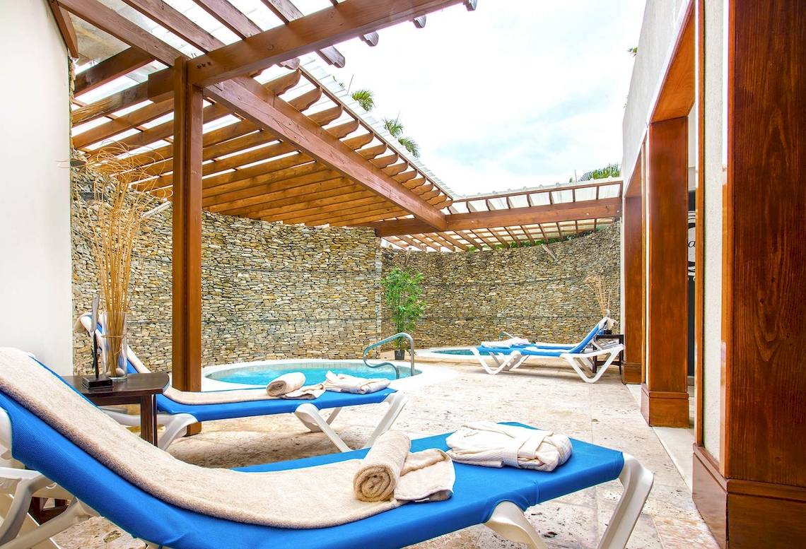Loungebereich im Marien Puerto Plata Hotel mit Außenpool und Liegestühlen.