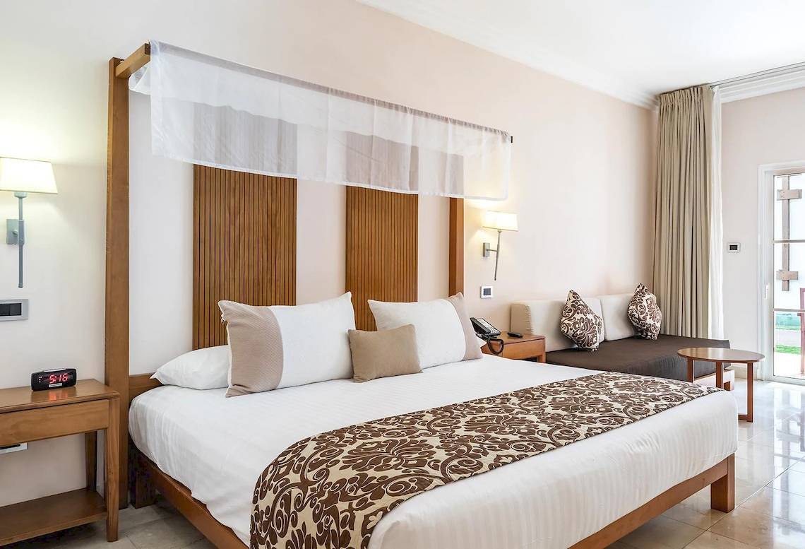 Hotelzimmer im Marien Puerto Plata mit Bett, Nachttisch, Sofa und Fenstern.