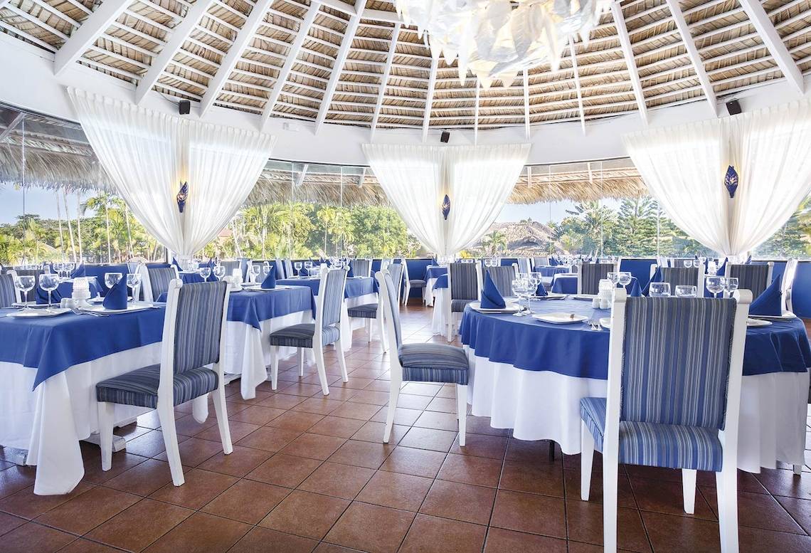 Innenansicht des Restaurants im Hotel Marien Puerto Plata mit blauen und weißen Tischdecken und Stühlen.