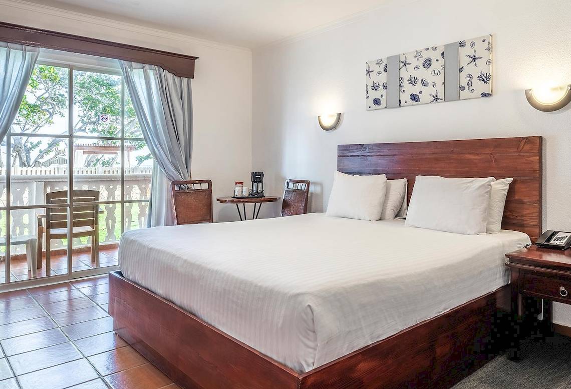 Marien Puerto Plata Hotel Schlafzimmer mit Bett, Fenstern und Balkon.