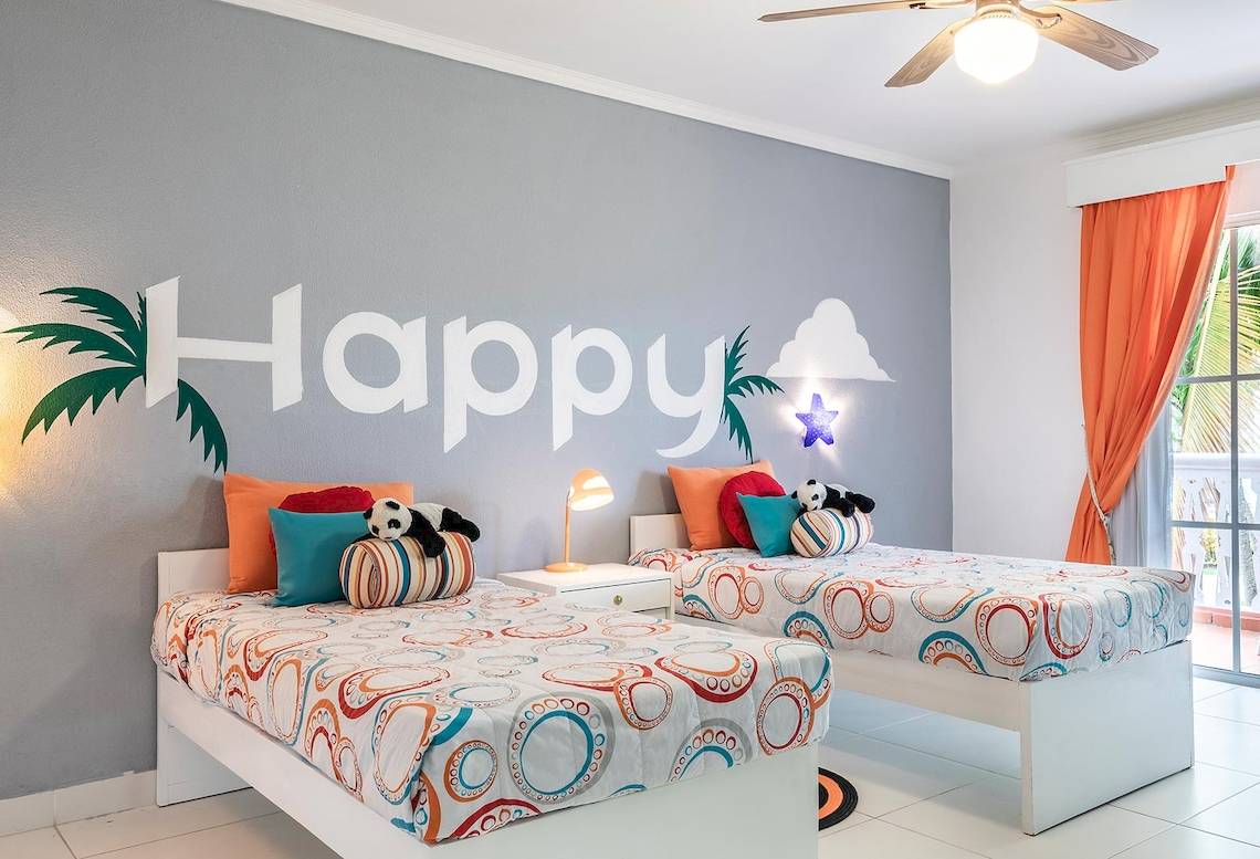 Zwei Betten im Zimmer mit 'Happy' Wandgestaltung, Marien Puerto Plata Hotel.