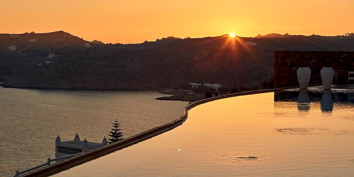 Sonnenuntergang am Pool der Myconian Villa Collection mit Blick auf das Meer und die Berge.