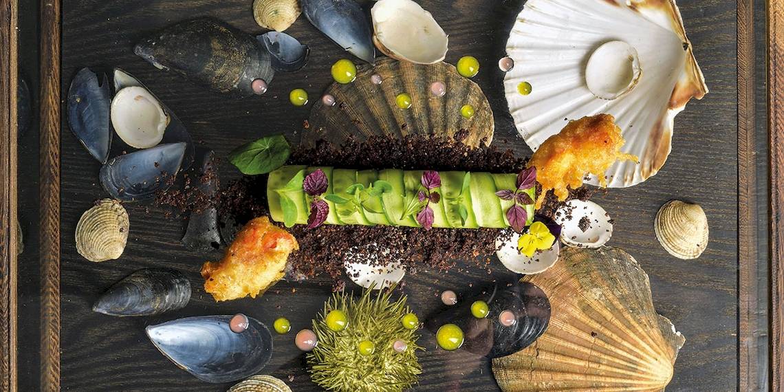 Kulinarisches Arrangement des Myconian Villa Collection mit Meeresfrüchten und grünem Gemüse