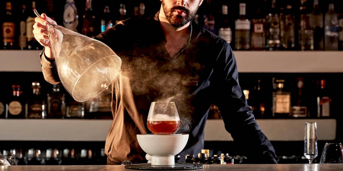 Barkeeper in einem Cocktail-Bar bei der Zubereitung eines Getränks mit einem Glas.