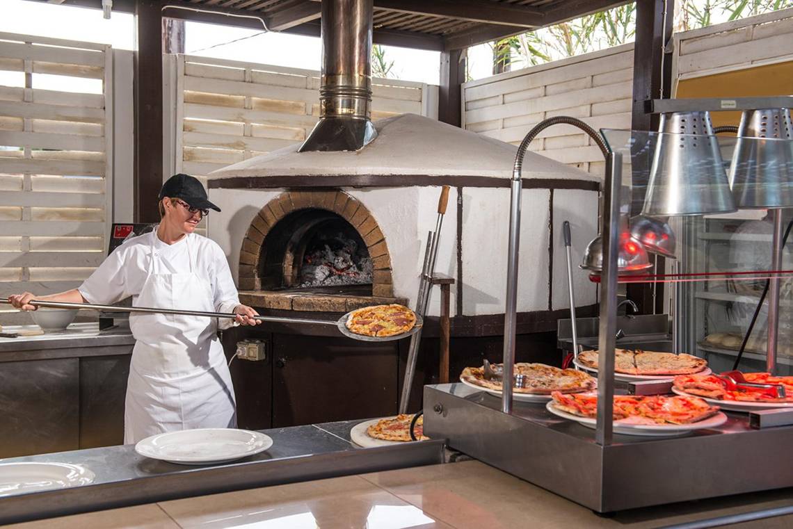 Koch bereitet Pizza im Holzofen im Gouves Water Park Holiday Resort zu.