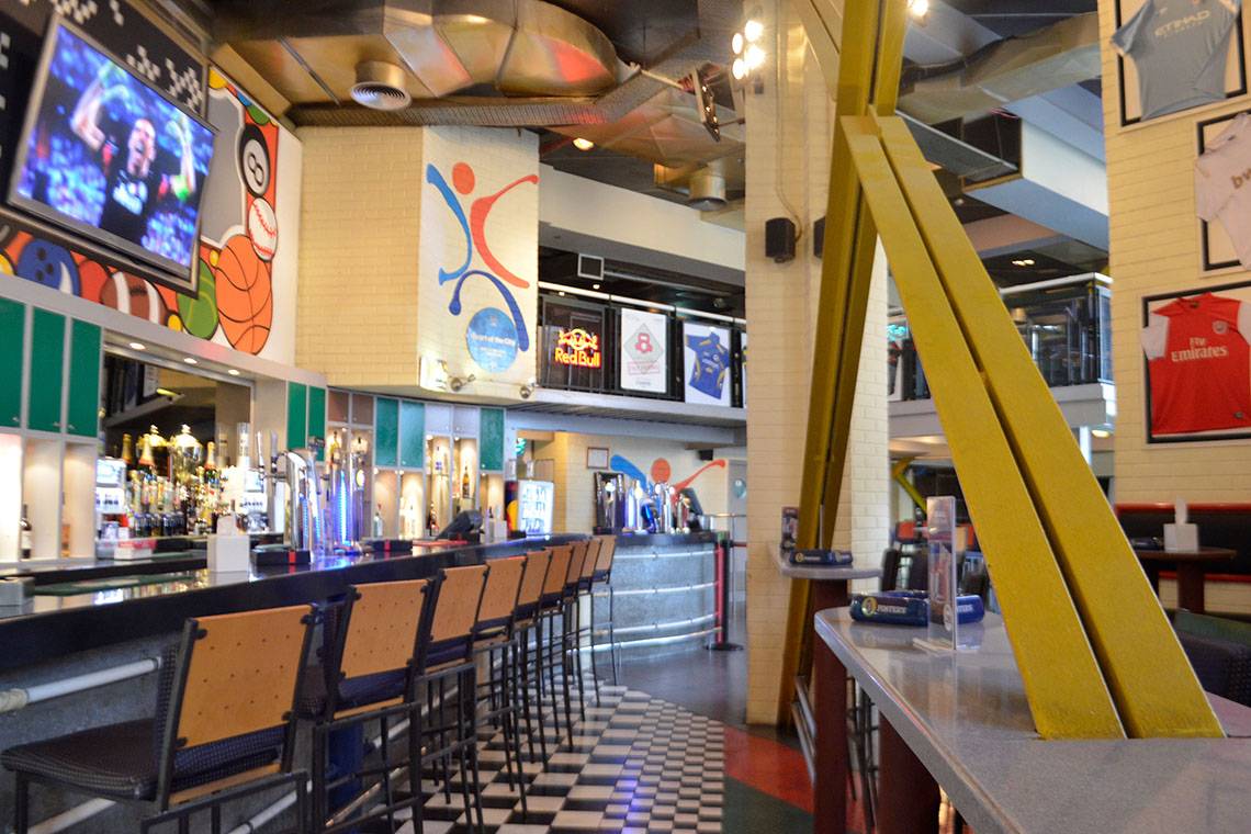Innenansicht der Bar im Le Meridien Abu Dhabi mit Barhockern, Theke und Fernsehern