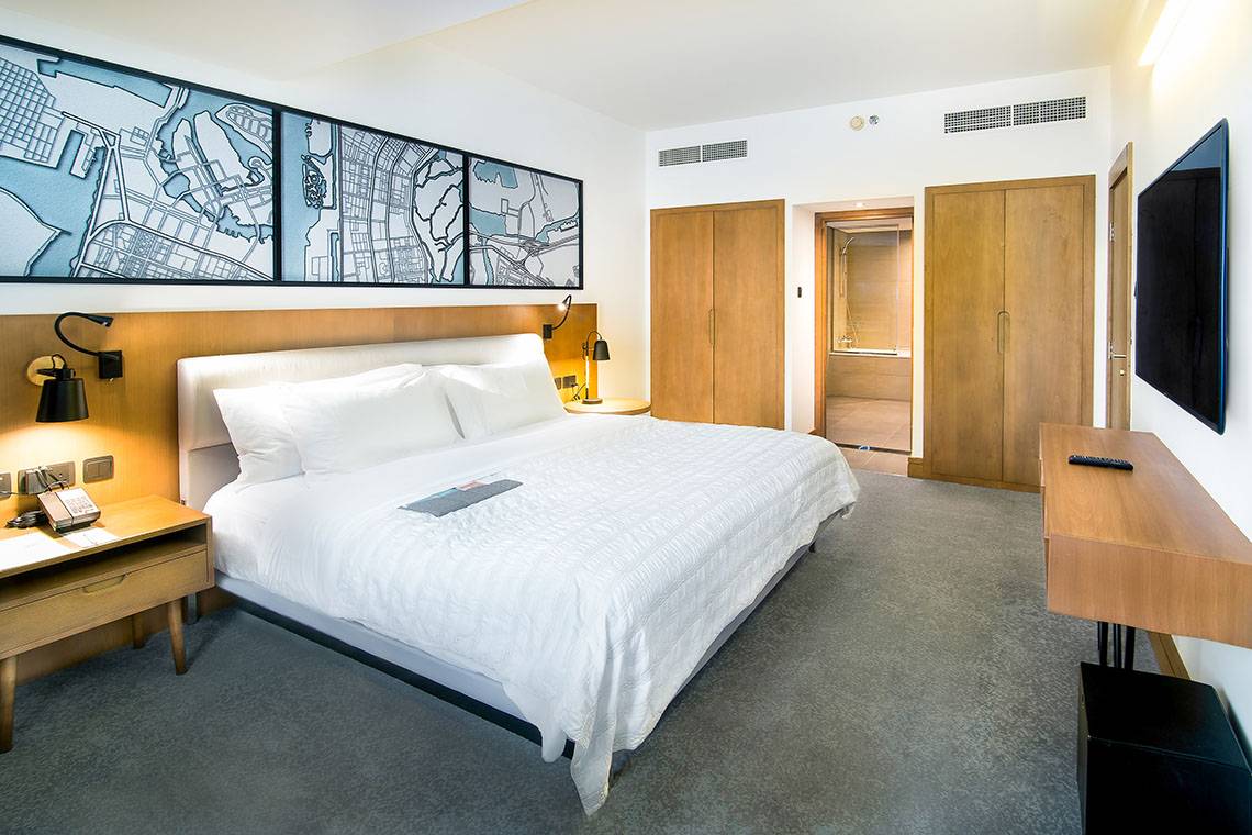 Innenansicht eines Hotelzimmers im Le Meridien Abu Dhabi mit Doppelbett, Nachttischen und Fernseher.