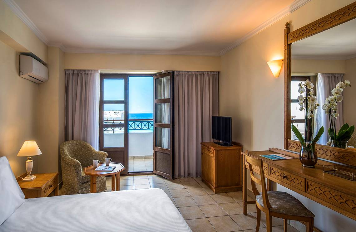 Innenansicht eines Zimmers im Mitsis Petit Palais Beach Hotel mit Meerblick.
