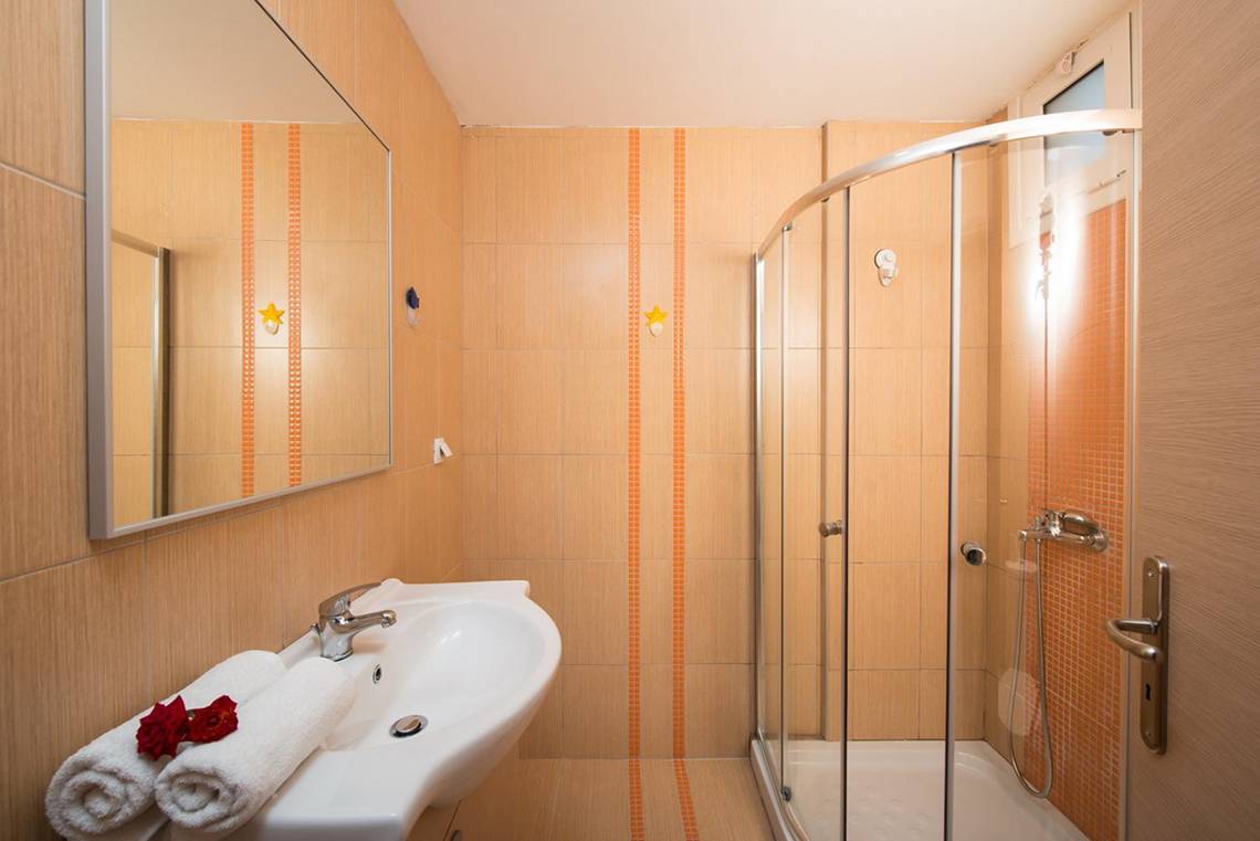 Badezimmer im Gouves Water Park Holiday Resort mit einer Dusche, einem Waschbecken und Handtüchern.
