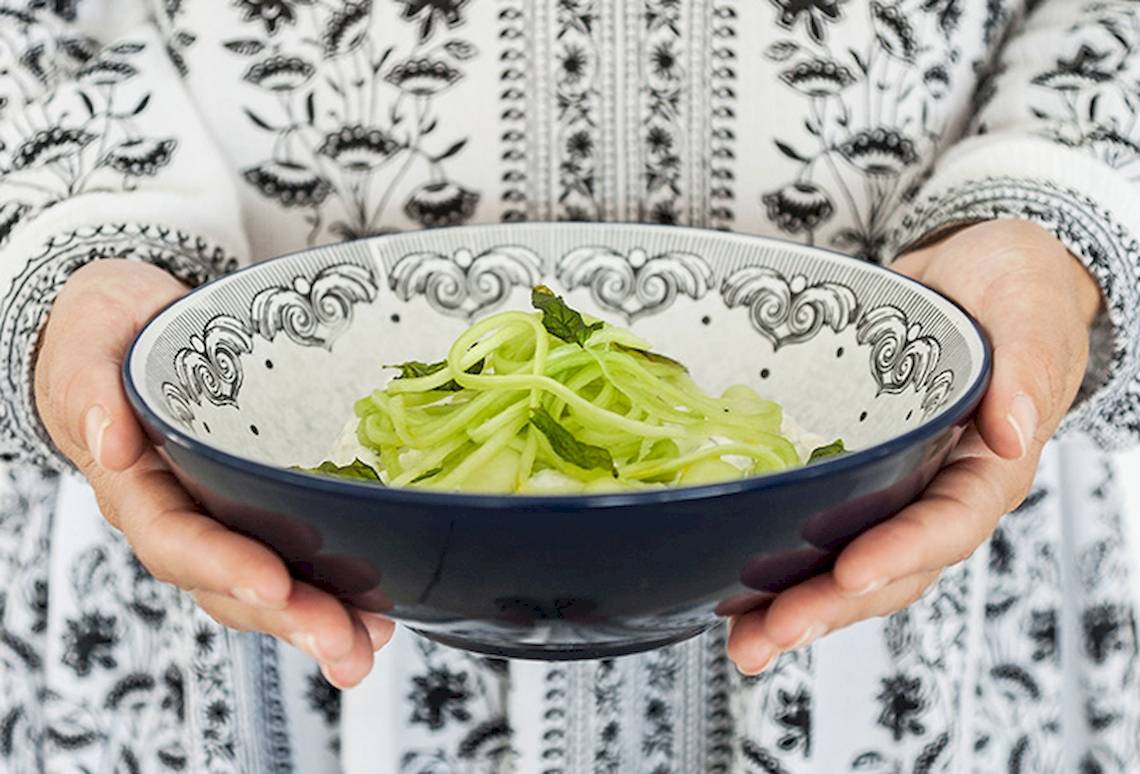 Hand hält Schüssel mit gewürztem Gurkensalat