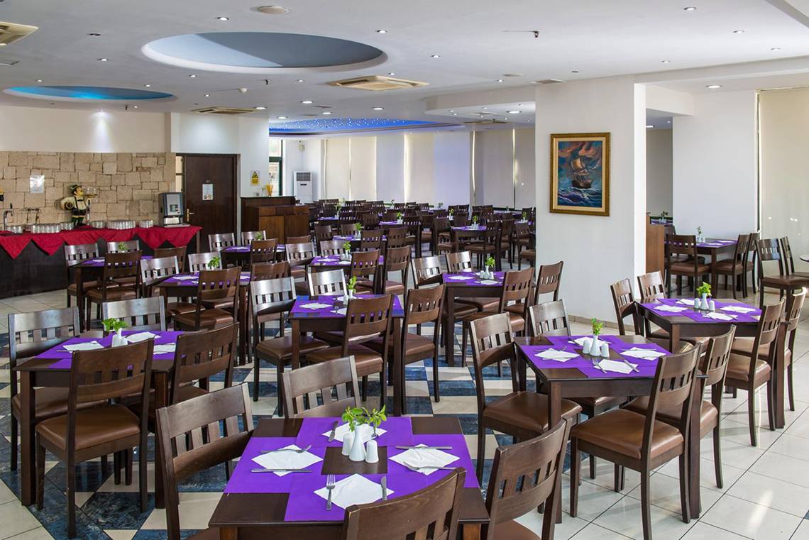Innenansicht des Restaurants im Gouves Water Park Holiday Resort mit gedeckten Tischen und Stühlen.