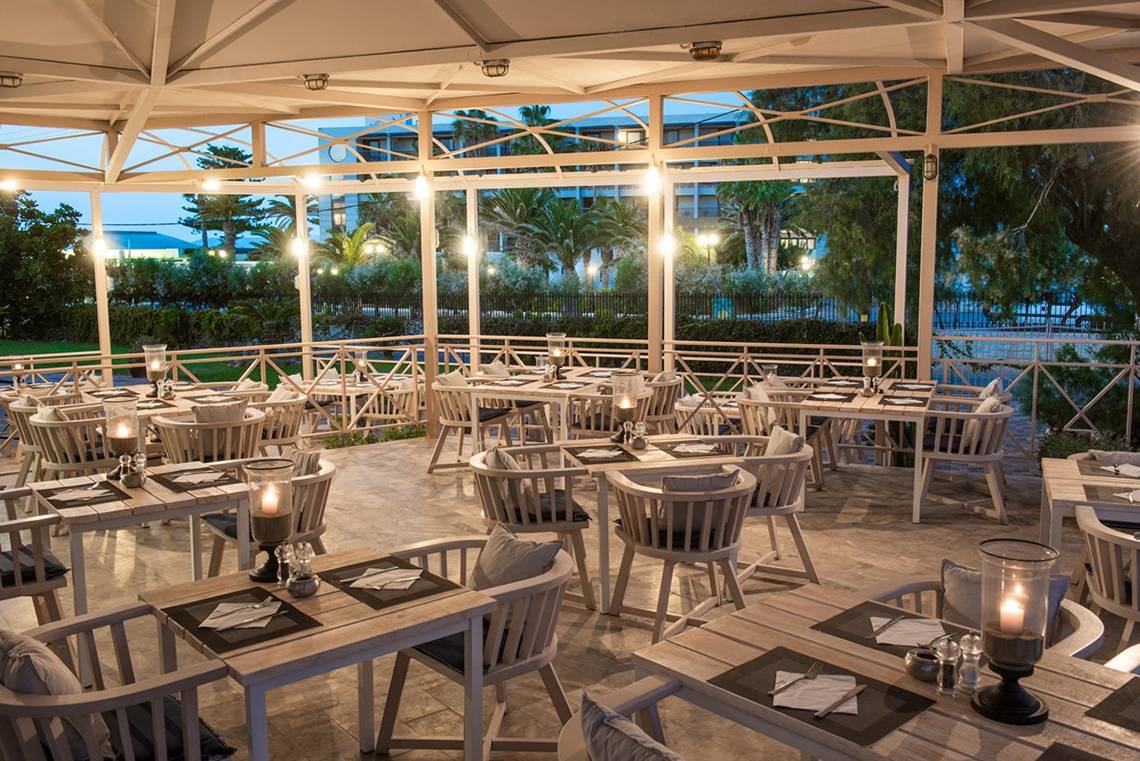 Außenbereich des Restaurants im Gouves Water Park Holiday Resort mit gedeckten Tischen und Stühlen.