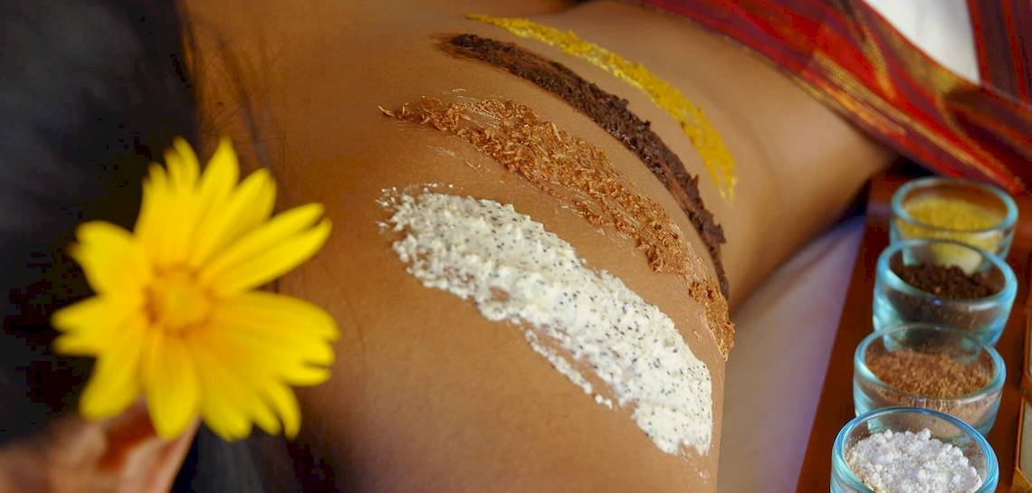 Spa-Behandlung im Kuredu Island Resort & Spa mit einer gelben Blume und verschiedenen Hautpflegeprodukten.