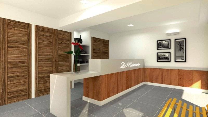 Rezeptionsbereich des Aparthotel Le Panoramic mit Holztüren, weißen Möbeln und Blumenvase.
