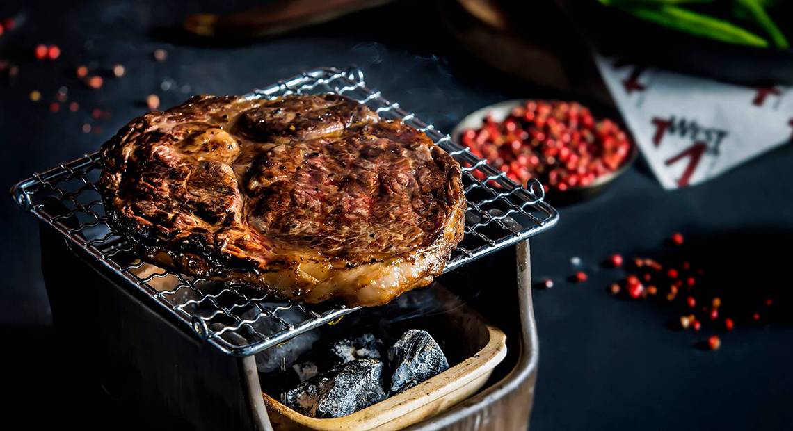 Ein Steak auf einem Grillrost mit Raucheffekten auf einem schwarzen Hintergrund.