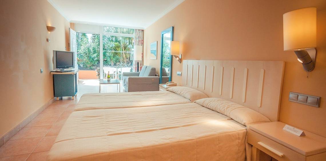 Doppelzimmer im IFA Altamarena Hotel mit zwei Betten, Fernseher, Couch und Fenstern