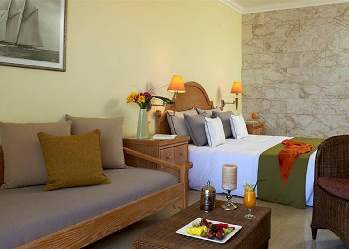Schlafzimmer im Atlantica Imperial Resort & Spa mit einem Bett, Sofa, Tisch und Dekoration.