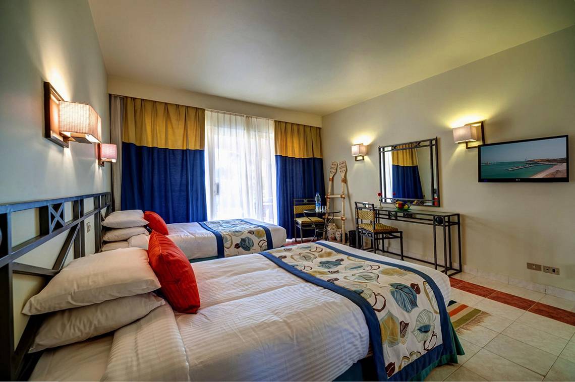 Hotelzimmer mit zwei Betten, Fernseher, Spiegel und Fenstern im LABRANDA Club Paradisio El Gouna.