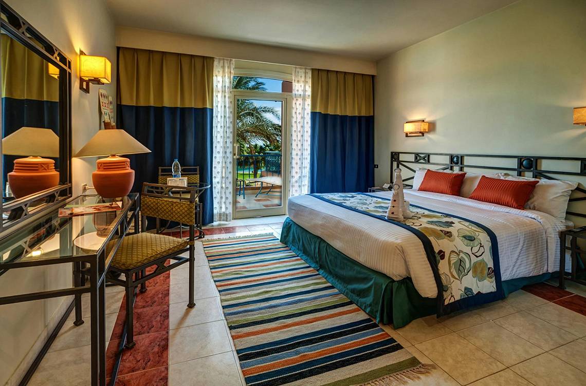 Ein Hotelzimmer im LABRANDA Club Paradisio El Gouna mit einem großen Bett, einer Sitzecke und einem offenen Balkon.