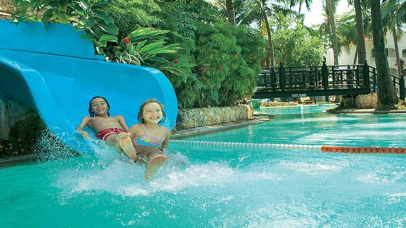 Zwei Kinder rutschen auf einer blauen Wasserrutsche im Sarova Whitesands Beach Resort & Spa.