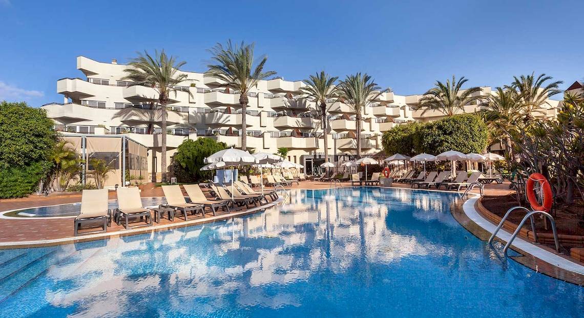 Außenpool des Barcelo Corralejo Bay Hotels mit Lounge-Stühlen und Sonnenschirmen.
