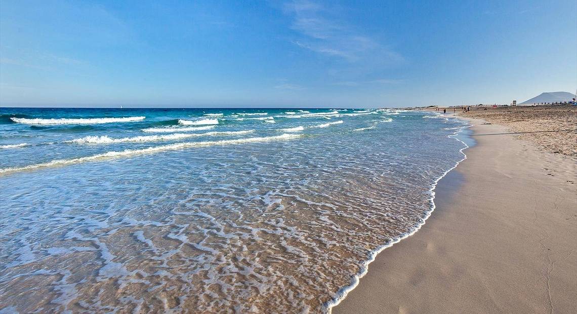 Strand mit blauem Himmel und Wellen am Barcelo Corralejo Bay Hotel