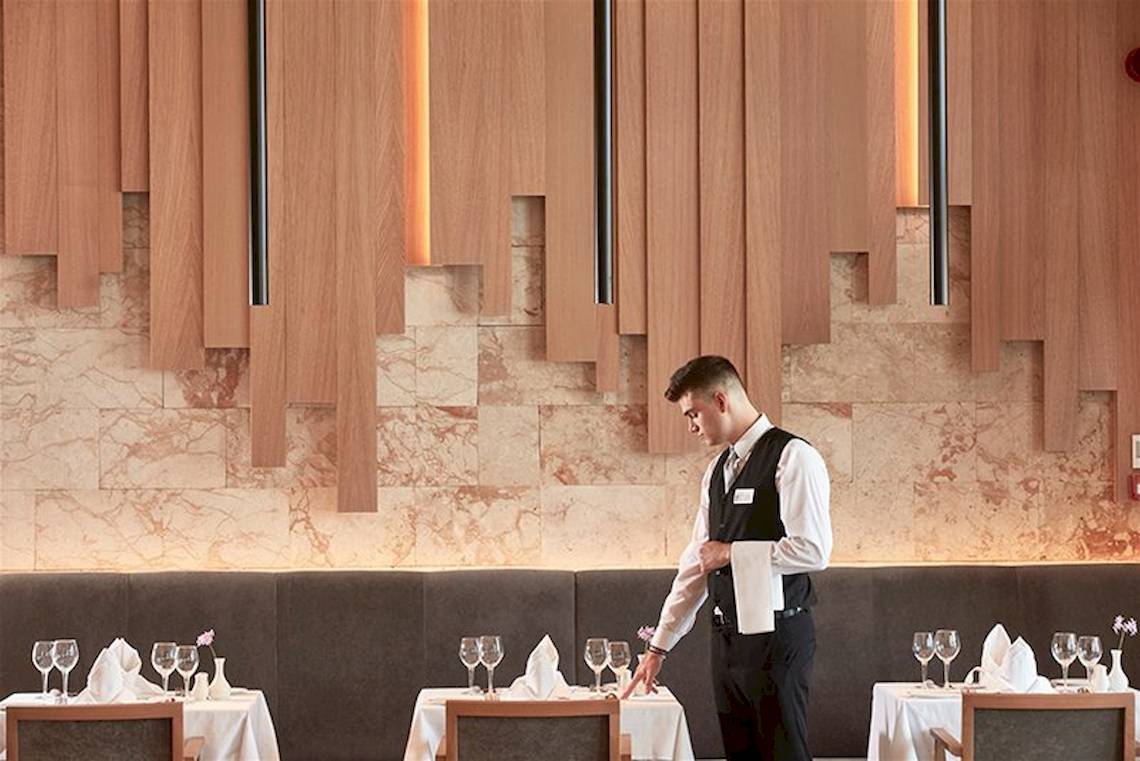 Ein Mitarbeiter des Atlantica Imperial Resort & Spa serviert ein Restaurant.