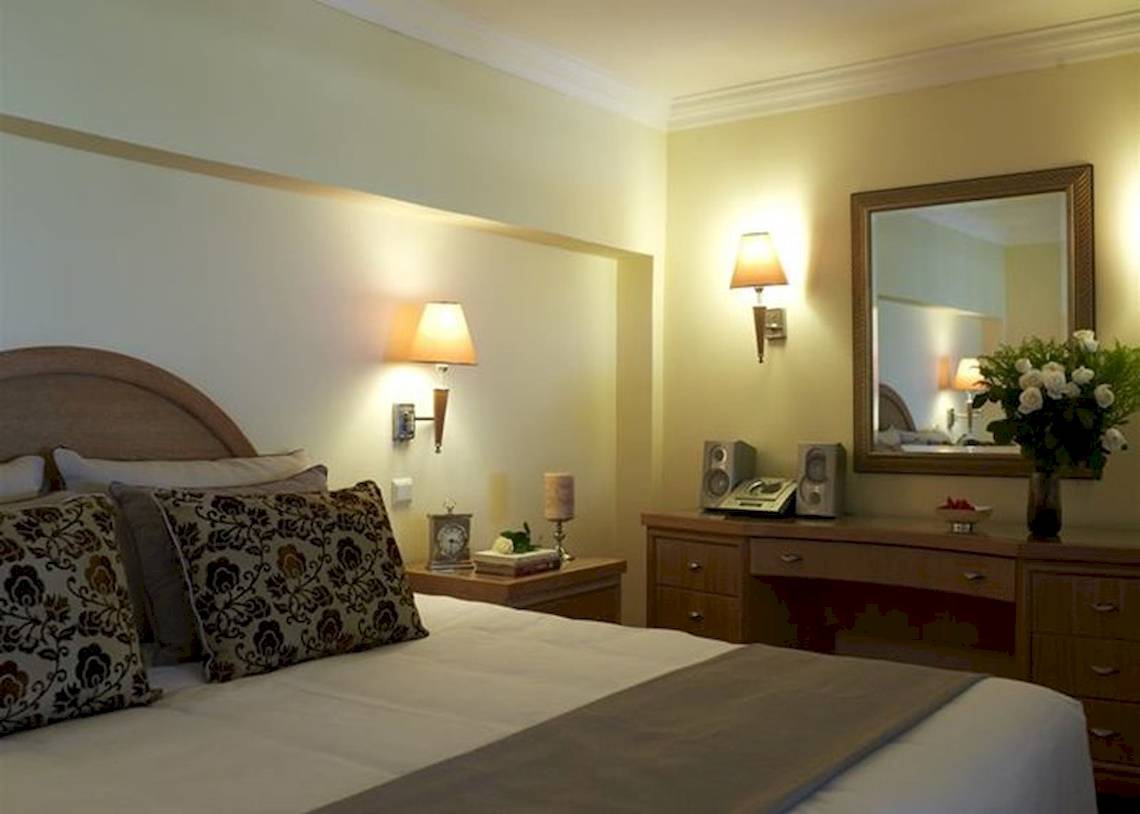Schlafzimmer im Atlantica Imperial Resort mit Bett, Nachttisch, Spiegel und Deko.