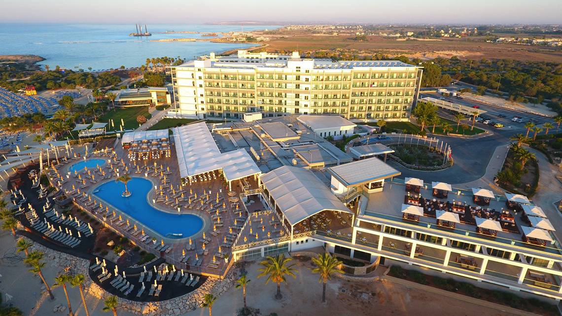 Luftaufnahme des Asterias Beach Hotels mit Swimmingpool und Meerblick.