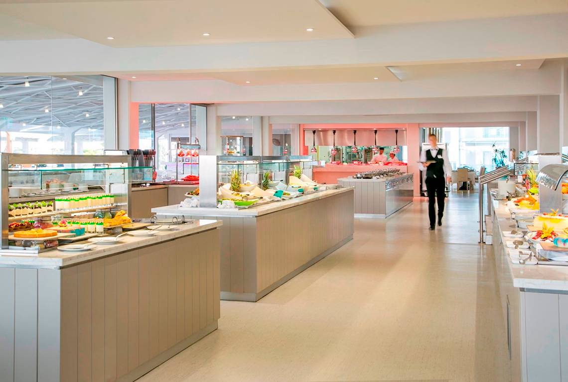 Buffetbereich im Asterias Beach Hotel mit verschiedenen Speisen und einem Kellner.