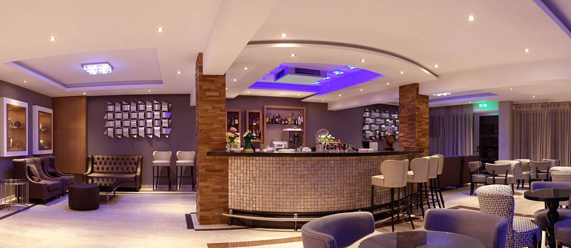 Innenansicht der Bar im Asterias Beach Hotel mit moderner Einrichtung und geometrischen Mustern.