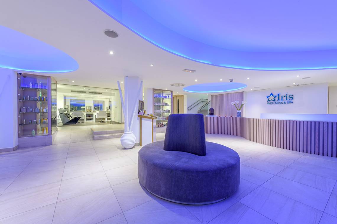 Wellnessbereich im Asterias Beach Hotel mit blauer Beleuchtung und runden Sitzmöbeln.