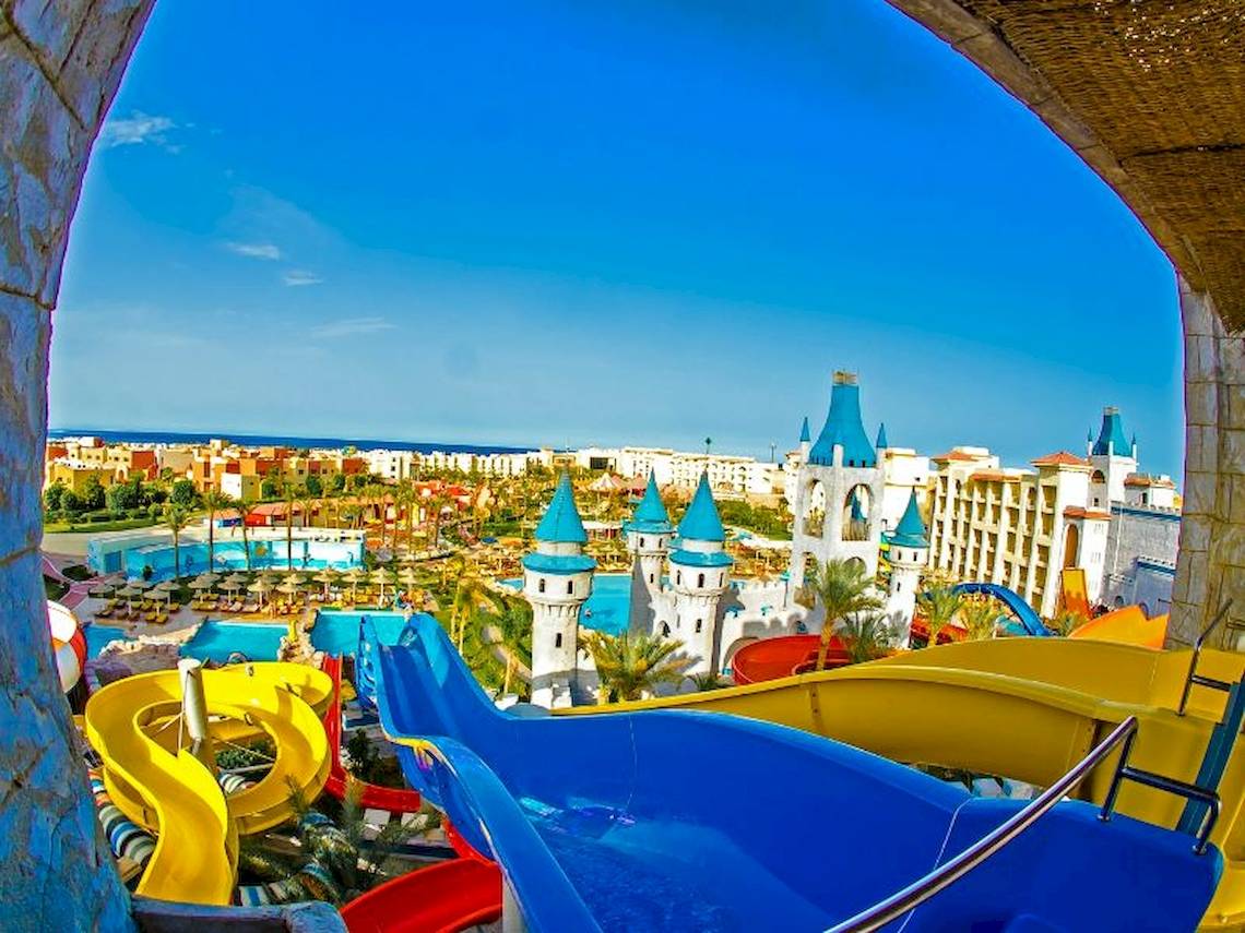 Aussicht auf den Wasserpark des Serenity Alma Heights Hotels mit bunten Rutschen und einem Schloss im Hintergrund.