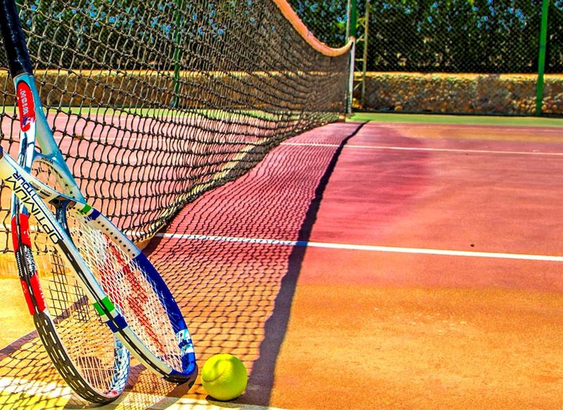 Tennisschläger neben einem Tennisball auf einem Tennisplatz.