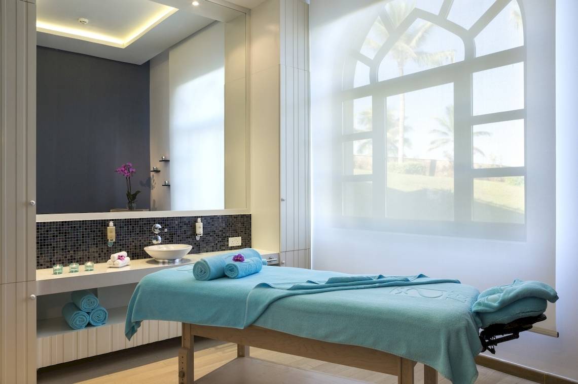 Spa-Behandlungsraum im Salalah Rotana Resort mit hellem Licht und Ausblick auf Palmen.
