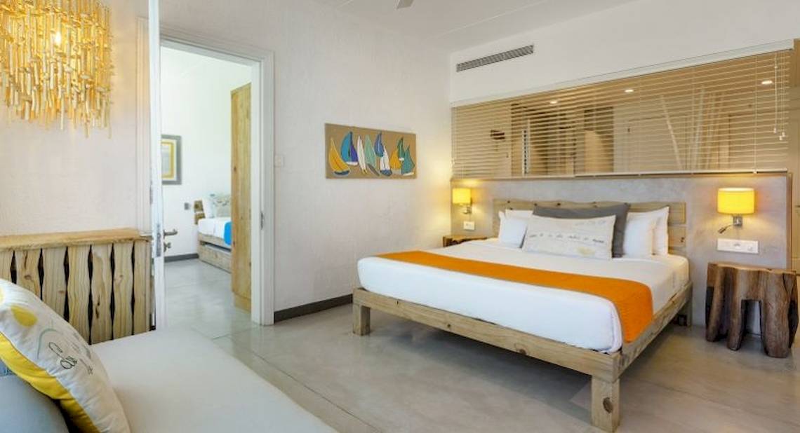 Das elegante Schlafzimmer im Zilwa Attitude Hotel mit einem großen Bett, Holzmöbeln und modernen Kunstwerken.