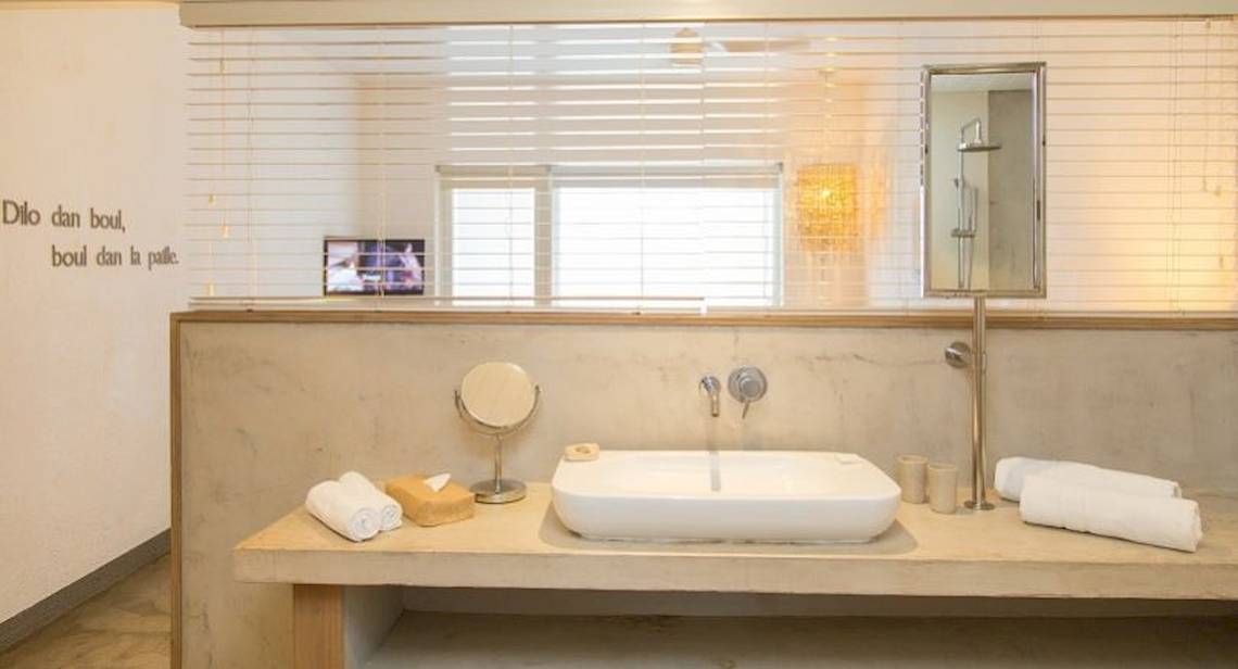 Ein Badezimmer im Zilwa Attitude Hotel mit einer weißen Wanne, Handtüchern, einem Spiegel und einer Fensterbank.