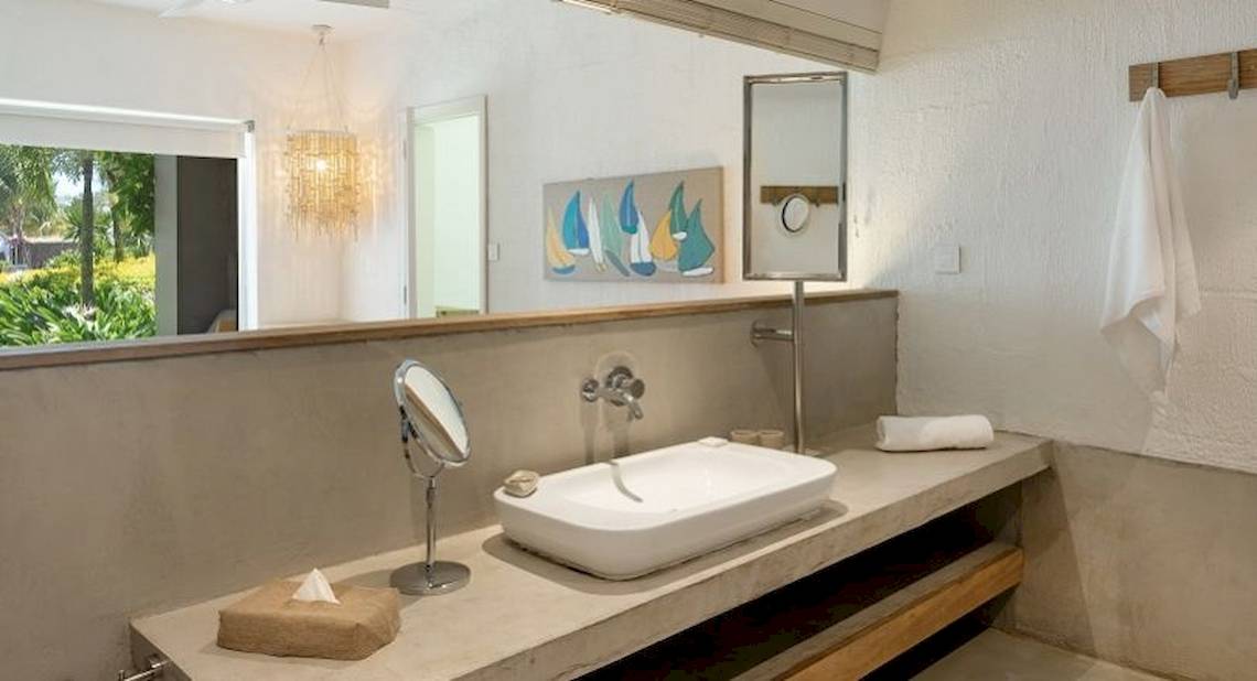 Badezimmer im Zilwa Attitude Hotel mit Spiegel, Waschbecken und Fenster.