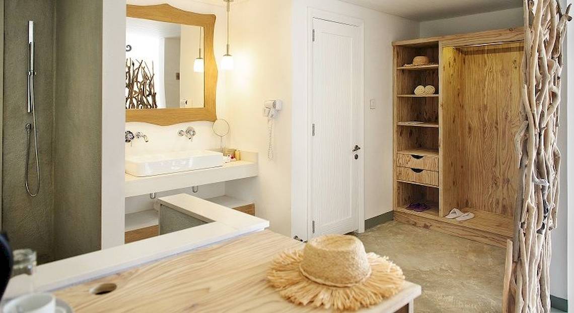 Badezimmer im Zilwa Attitude Hotel mit weißem Waschbecken, Spiegel und Holzschrank.