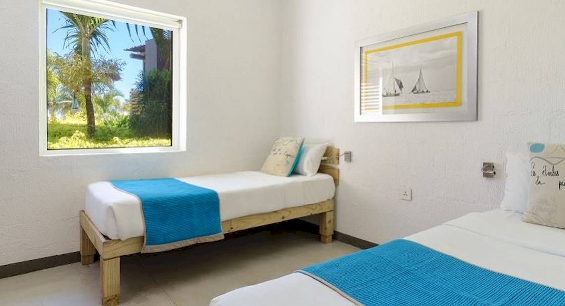Doppelzimmer mit zwei Betten und Ausblick auf eine tropische Landschaft