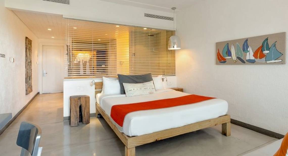 Ein modernes Hotelzimmer im Zilwa Attitude Hotel mit einem Bett, Kissen, Decken und einer Wanddekoration.